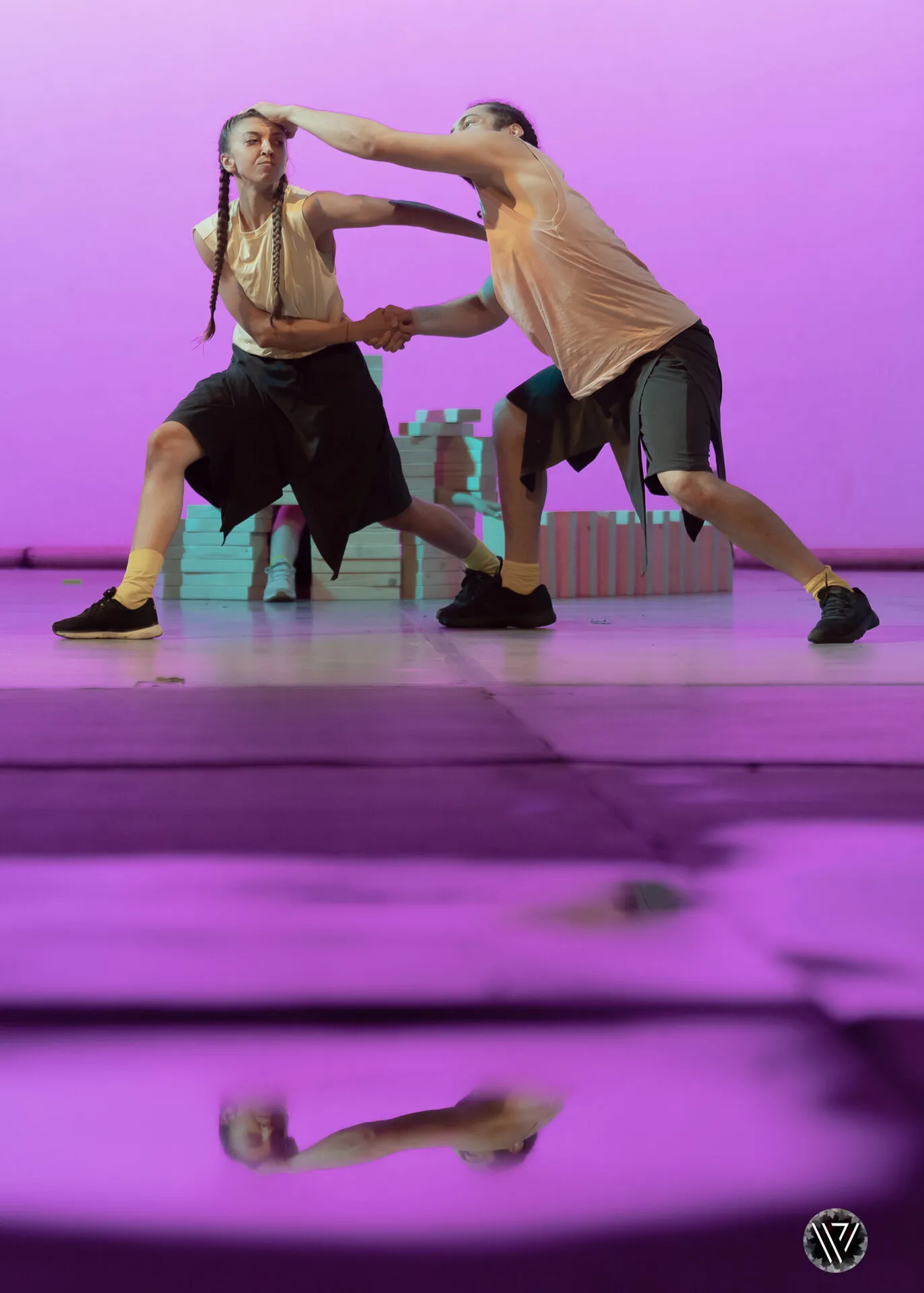 Two performers grappling under purple light