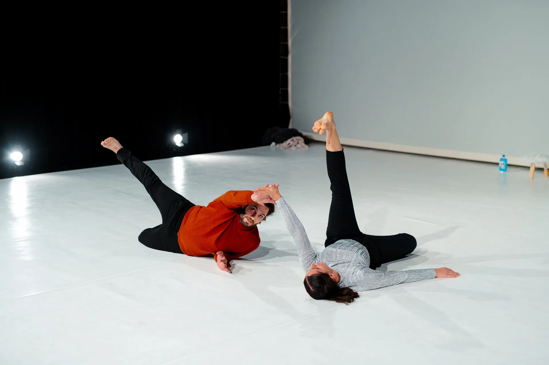 Two dancers in a floor duet on a white stage