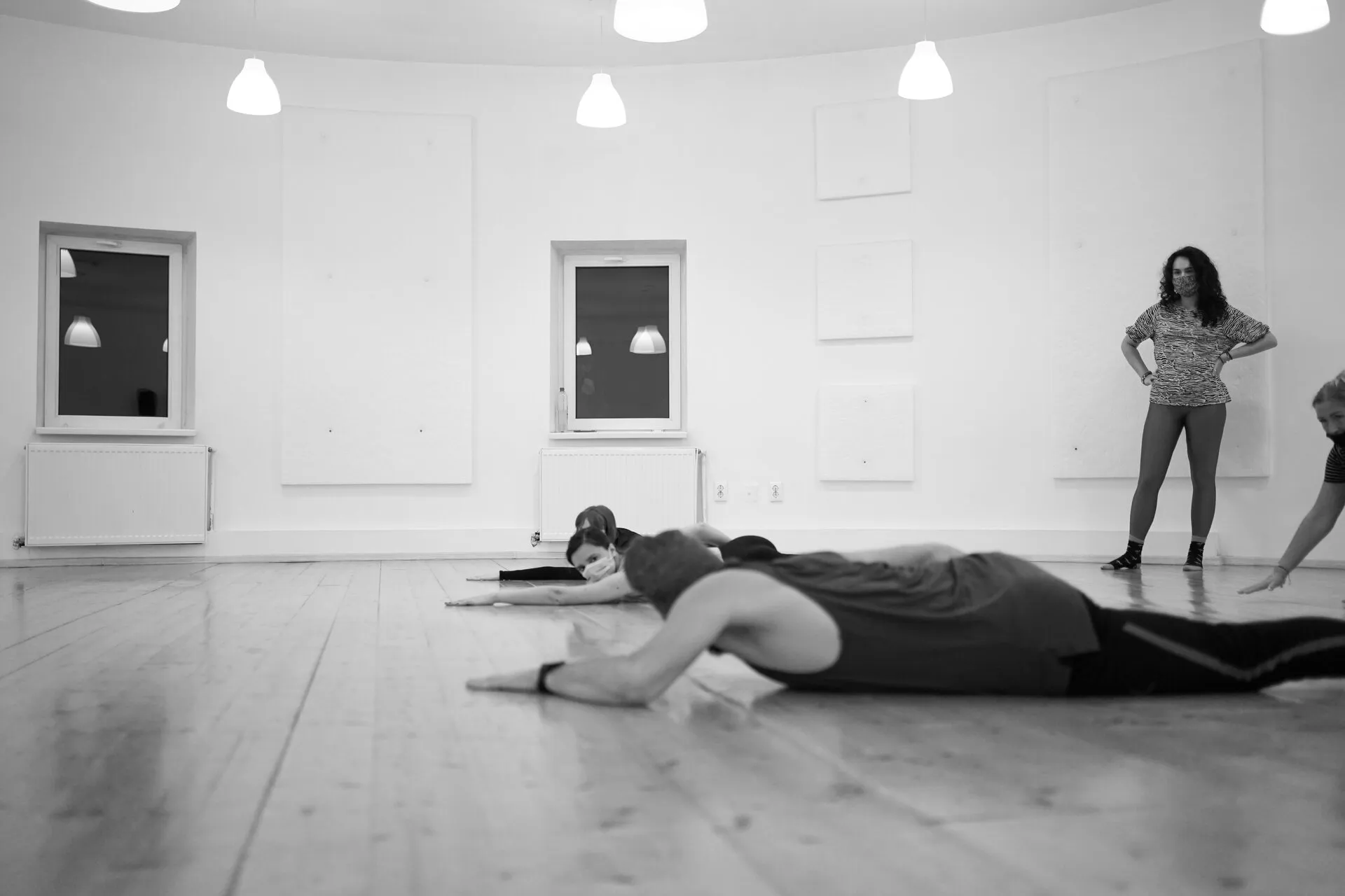 Black-and-white photo of a dancer lying on a wooden studio floor