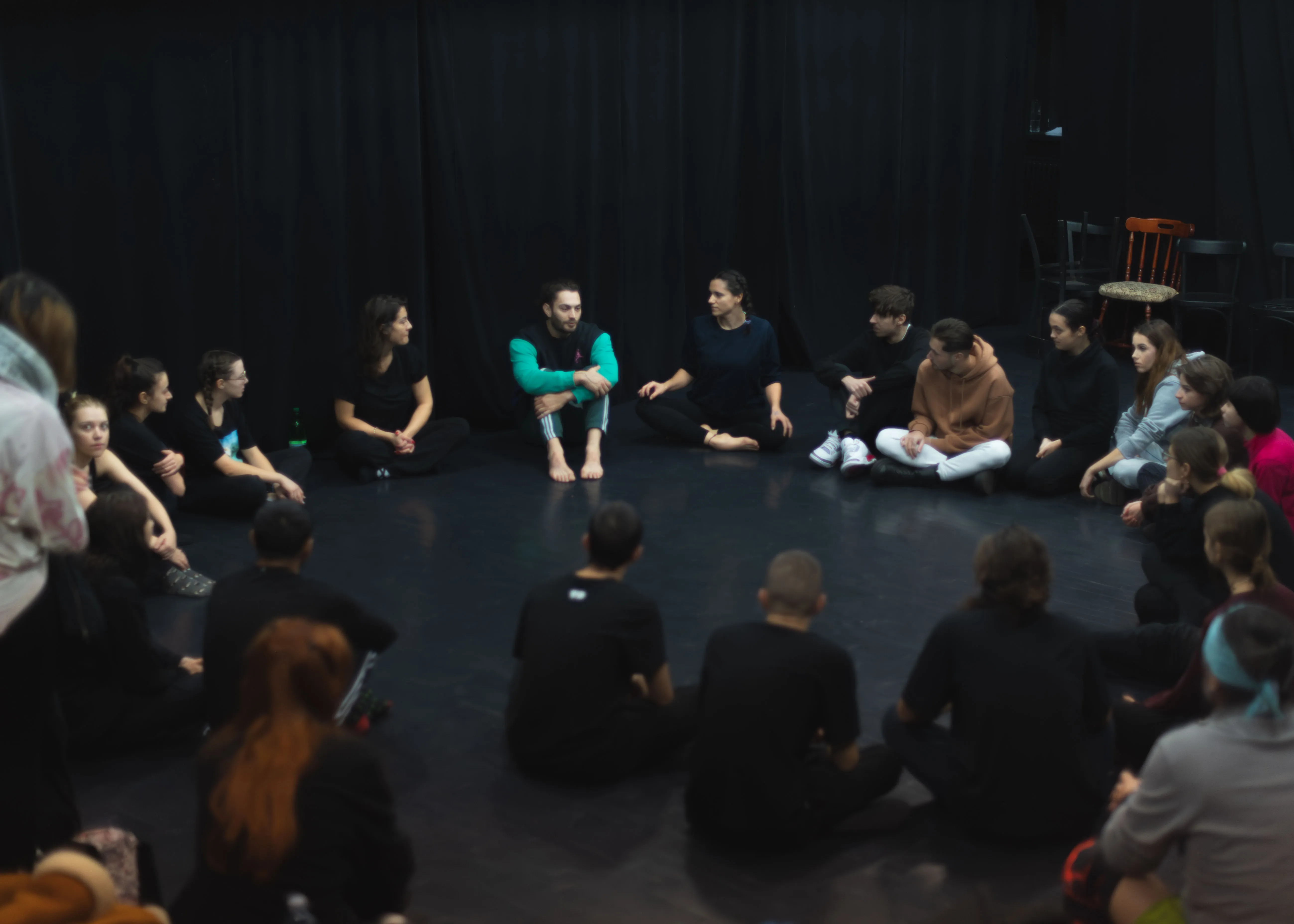 Workshop circle seated on a black studio floor