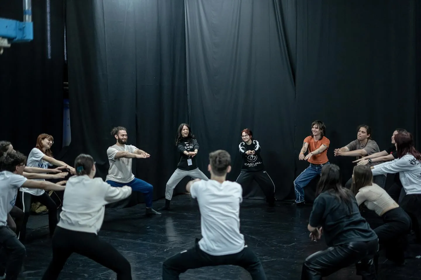 Workshop participants in a wide low stance in a black-box studio